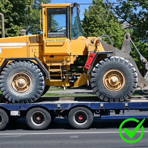 Mobile equipment being transported on a flatbed trailer