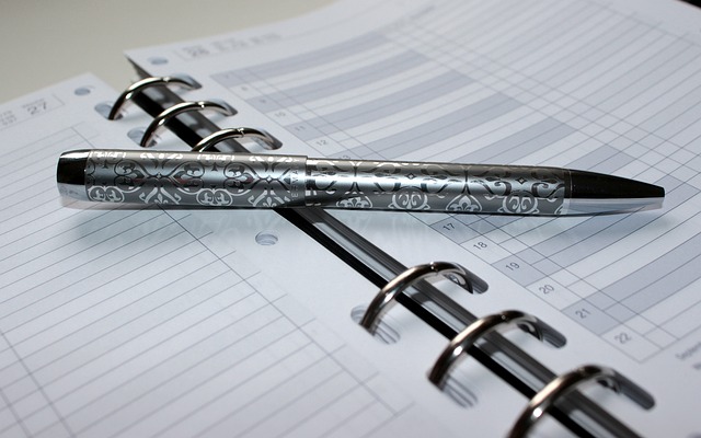 An open planner with a pen laying on the pages ready to schedule events