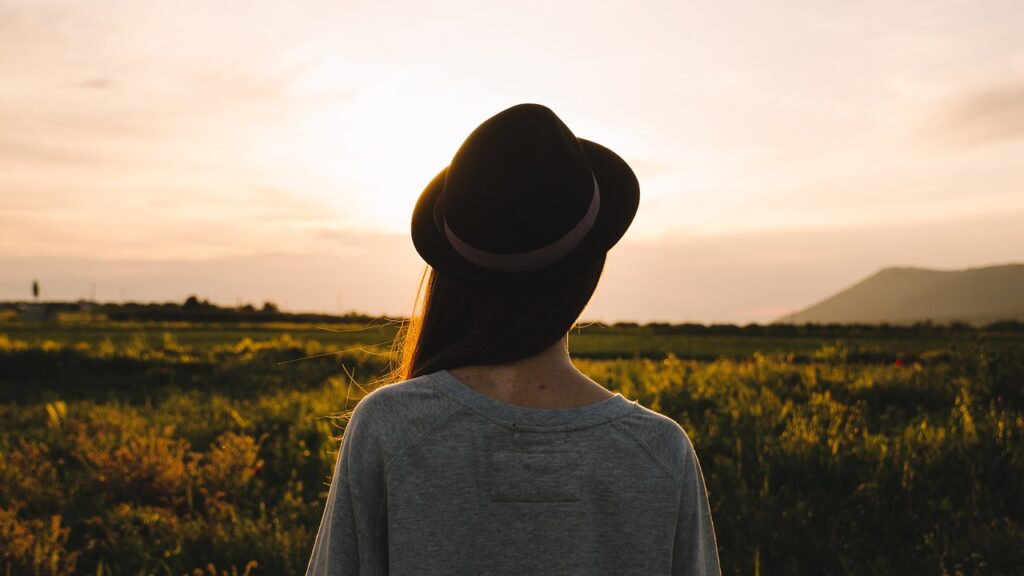 Woman standing in a pasture at dusk gazing at horizon