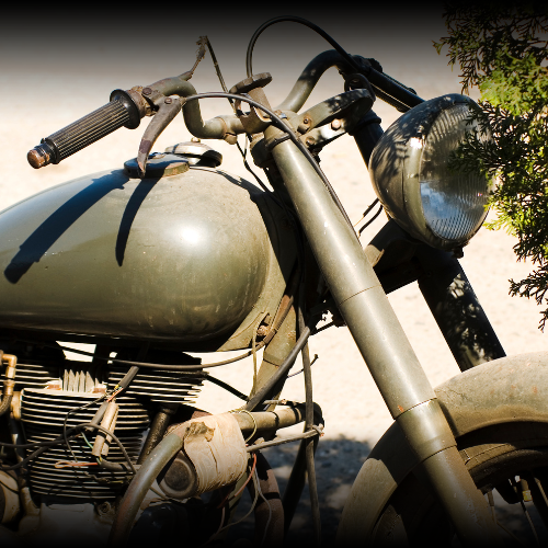 A vintage motorcycle is showcased, highlighting the handlebars, headlamp, engine, and front wheel, symbolizing the classic bikes that often require special consideration under motorcycle insurance policies due to their age and unique characteristics