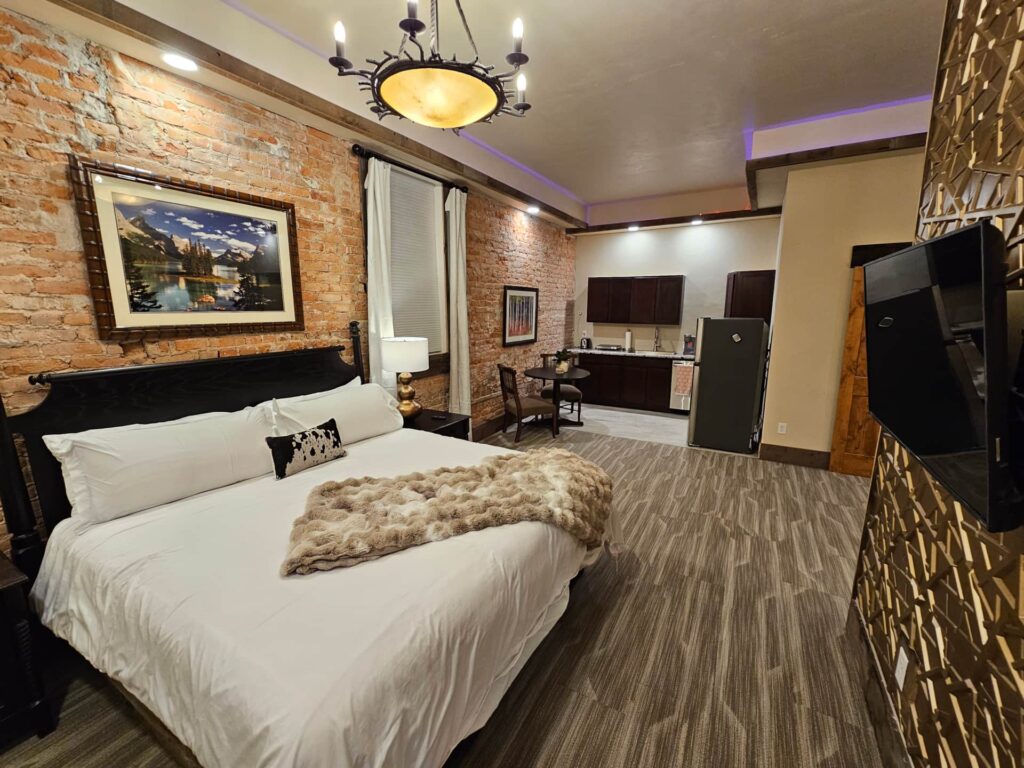 Deluxe Studio Suite at Eaglescape Suites & Event Center with a plush king-size bed, fully equipped kitchen, well-appointed private bathroom, and stylish, airy interior with 11-foot ceilings and adjustable lighting.