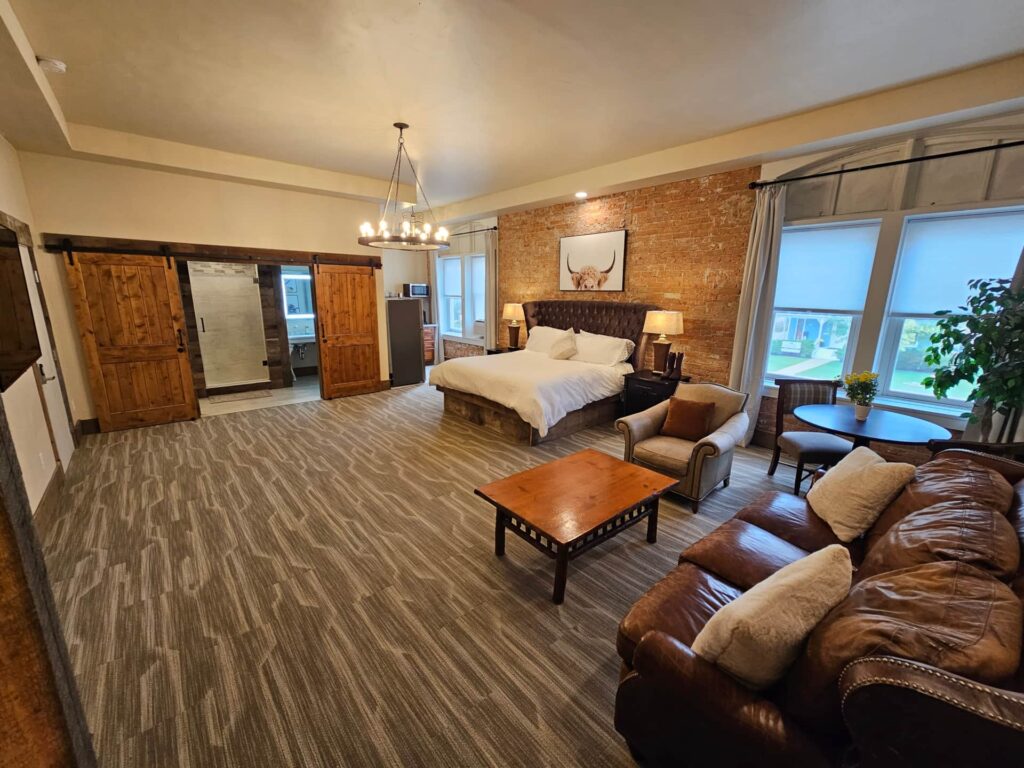 Luxury Studio Suite at Eaglescape Suites & Event Center featuring a custom double-queen bunk bed, additional bed, lounge seating, kitchenette, exposed brick accents, and a spacious, stylish layout for relaxation